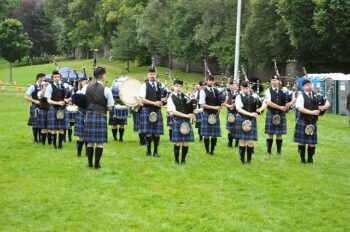 Men playing bag pipes in field