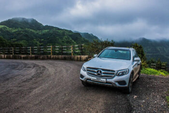 image of a mercedes parked with clouds and hills in the background