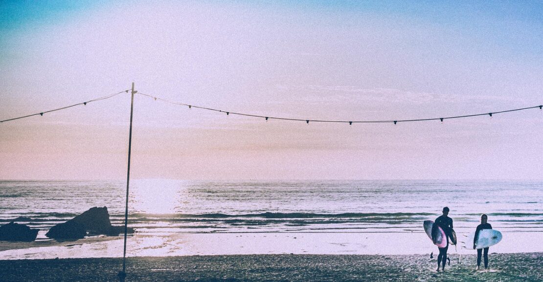 image of two people surfing on a beach